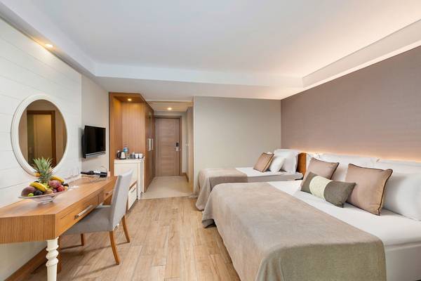 Hotelzimmer im Sherwood Exclusive Kemer mit zwei Betten, Schreibtisch und Fernseher.
