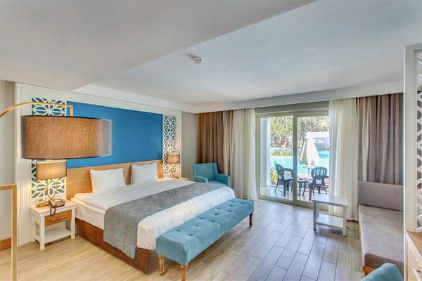 Innenansicht eines Schlafzimmers im Sherwood Exclusive Kemer Hotel mit Blick auf den Pool.