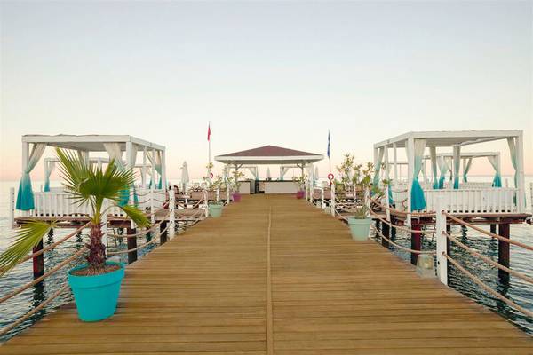 Ansicht des Sherwood Exclusive Kemer Piers mit Gehweg, Pavillons und Pflanzen in Blautönen.