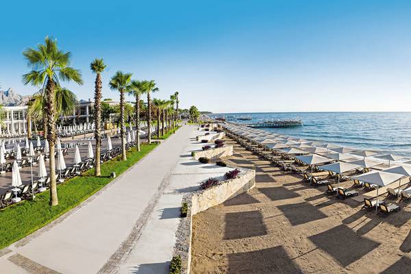 Luftaufnahme des Sherwood Exclusive Kemer Hotels mit Palmen und Sonnenschirmen am Strand