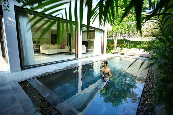 Mann im Pool des TIA Wellness Resorts neben der Terrasse mit Möbeln.