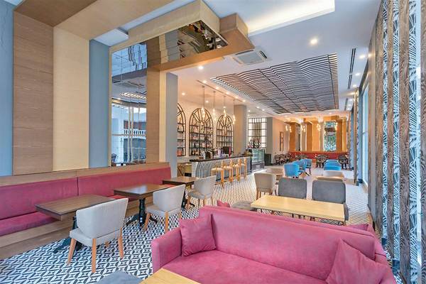 Loungebereich des Sherwood Exclusive Kemer Hotels mit roten Sofas, Tischen und Stühlen.