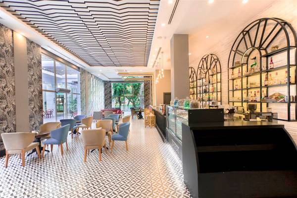 Innenbereich des Sherwood Exclusive Kemer Hotels mit geometrischem Bodenmuster, modernen Möbeln und einer Bar.