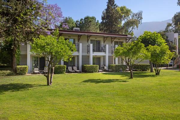 Außenansicht des Sherwood Exclusive Kemer Hotels mit Rasen und Bäumen.