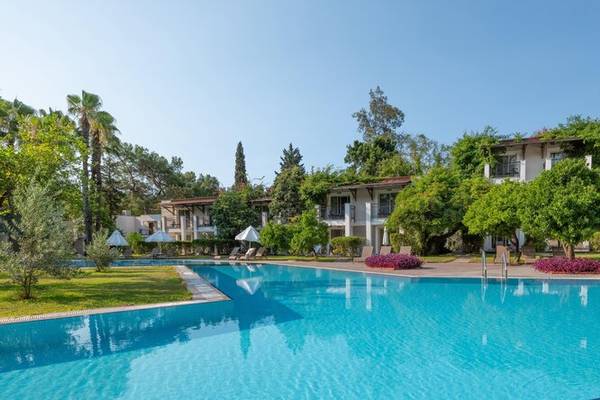 Sherwood Exclusive Kemer Hotel Außenbereich mit Pool, Bäumen und Gebäuden.