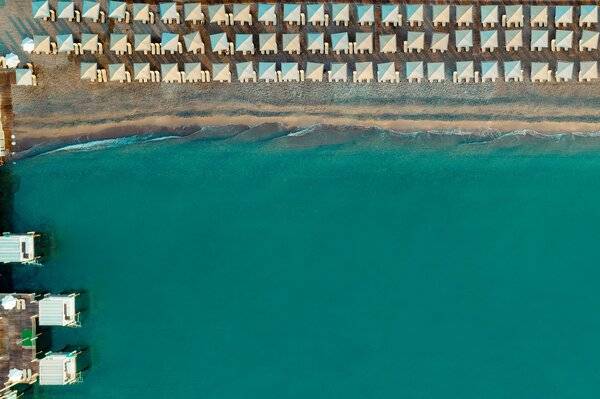 Luftaufnahme des Sherwood Exclusive Kemer Hotels mit vielen weißen Sonnenschirmen am Strand