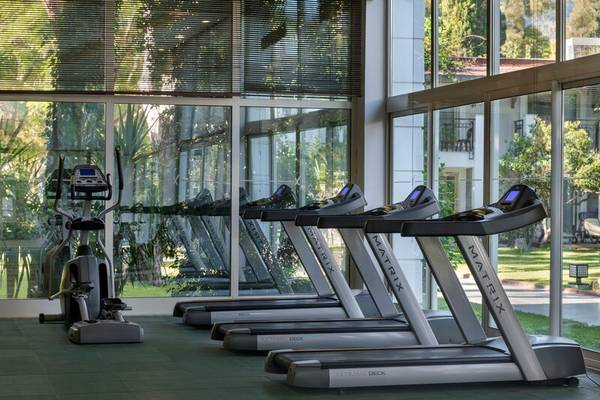 Fitnessraum des Sherwood Exclusive Kemer Hotels mit einer Reihe von Laufbändern und einem Stepper.