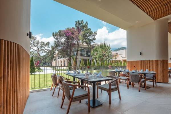 Terrasse des Sherwood Exclusive Kemer Hotels mit Blick auf einen gepflegten Rasen und Bäume
