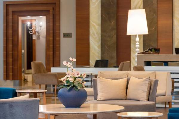 Lobby des Sherwood Exclusive Kemer Hotels mit Blumenvase und Möbeln.