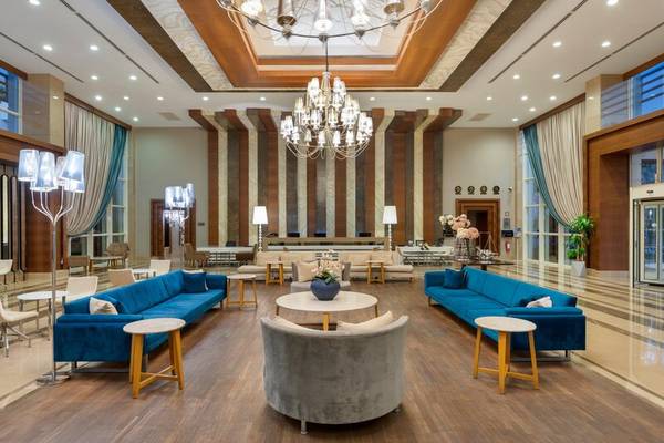 Hotellobby des Sherwood Exclusive Kemer mit blauen Sofas, Kronleuchter und modernen Möbeln.