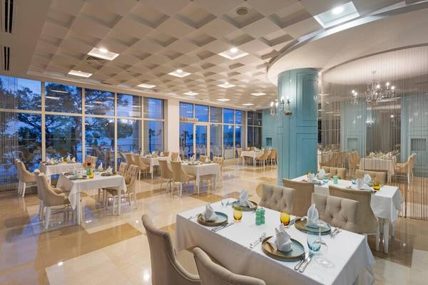 Innenansicht des Restaurants im Sherwood Exclusive Kemer Hotel mit gedeckten Tischen und Stühlen.