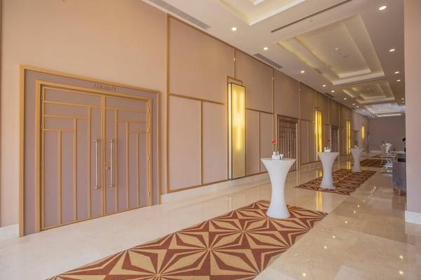 Eingangsbereich des Sherwood Exclusive Kemer Hotels mit Marmorboden, goldenen Türen und weißen Stehtischen.