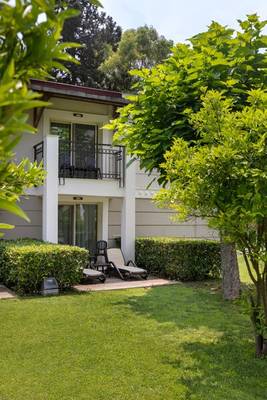 Außenbereich des Sherwood Exclusive Kemer Hotels mit grünem Rasen und Lounge-Stuhl.