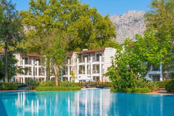 Außenansicht des Sherwood Exclusive Kemer Hotels mit Swimmingpool und grüner Landschaft.