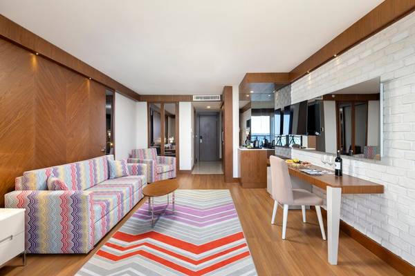Suite-Inneneinrichtung im Sherwood Exclusive Kemer mit Couch, Tisch, Sessel und Arbeitsbereich.