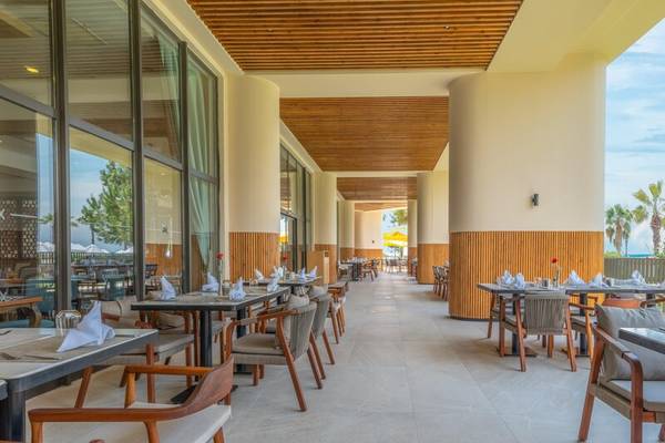 Innenbereich des Restaurants im Sherwood Exclusive Kemer Hotel mit Tisch, Stühlen und freien Plätzen.