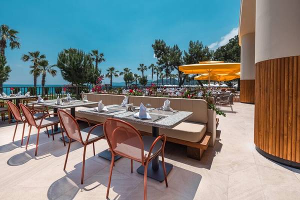 Terrasse des Sherwood Exclusive Kemer Hotels mit Sitzen und Tischen, die zum Meer ausgerichtet sind.