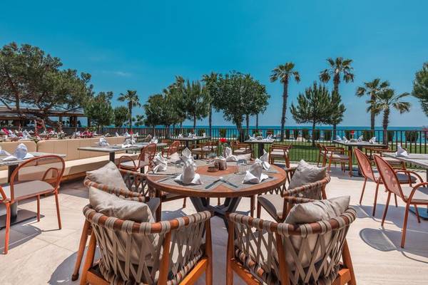 Außenterrasse des Sherwood Exclusive Kemer Hotels mit Blick auf das Meer und Palmen.