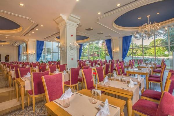 Innenraum des Restaurants des Sherwood Exclusive Kemer Hotels mit gedeckten Tischen und Stühlen.