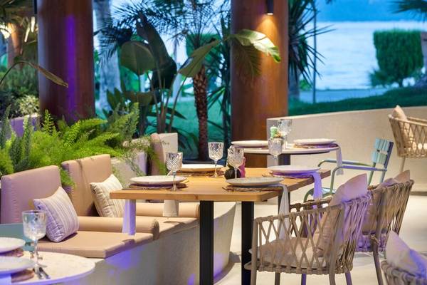 Innenbereich des Sherwood Exclusive Kemer Hotels mit gedeckten Tischen und Blick auf den Garten und das Meer.