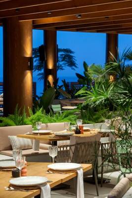 Innenansicht des Restaurants im Sherwood Exclusive Kemer Hotel mit Tisch, Stühlen und Pflanzen.