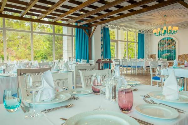Innenansicht des Restaurants im Sherwood Exclusive Kemer mit gedeckten Tischen und Stühlen.