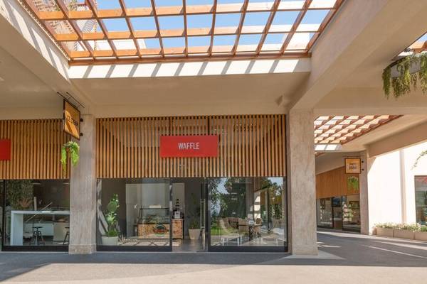 Außenansicht des Sherwood Exclusive Kemer Hotels mit einem Eingang zu einem Laden, der 'WAFFLE' beschriftet ist.