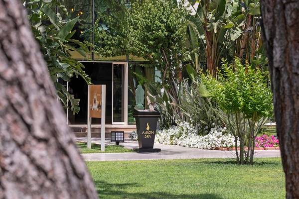 Außenansicht des Sherwood Exclusive Kemer Hotels am Tag mit Garten und Spa-Bereich.