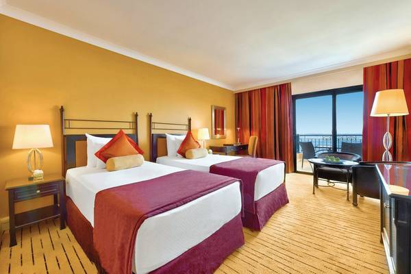 Doppelzimmer im Corinthia St. George's Bay mit Meerblick, zwei Betten, Schreibtisch und Balkon.