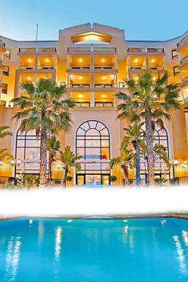 Außenansicht des Corinthia St George's Bay Hotels mit Swimmingpool und Palmen