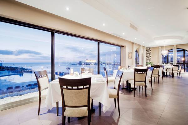 Innenansicht des Restaurants im Corinthia St George's Bay Hotel mit Blick auf das Meer.