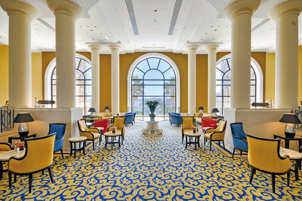 Lobby des Corinthia St. George's Bay Hotels mit gelben und blauen Mustern und großen Fenstern.