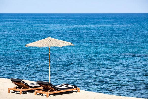 Strand mit Sonnenliegen und Sonnenschirm vor dem Meer