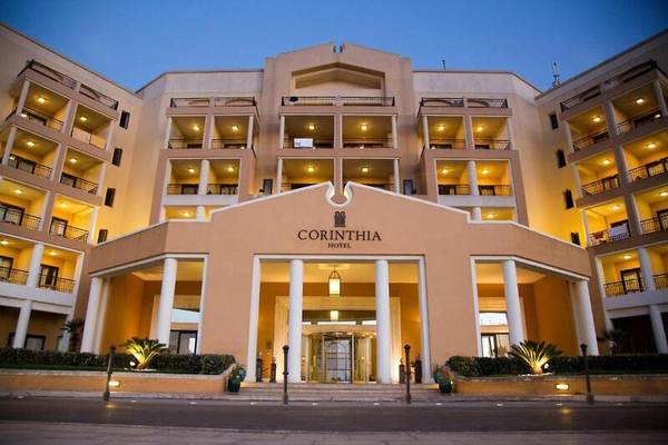 Die Vorderansicht des Corinthia St. George's Bay Hotels bei Nacht mit Beleuchtung.