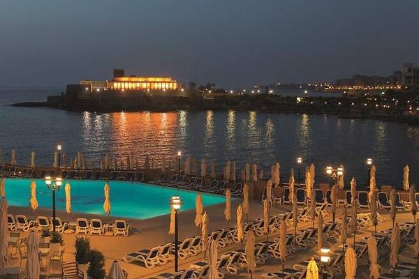 Abendansicht des Corinthia St George's Bay Hotels mit Swimmingpool und Meerblick