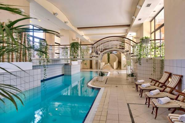 Innenpoolbereich des Corinthia St George's Bay Hotels mit Loungestühlen und Pflanzen.