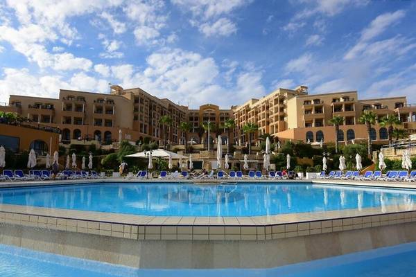 Außenpool des Corinthia St. George's Bay Hotels mit Sonnenliegen und Sonnenschirmen