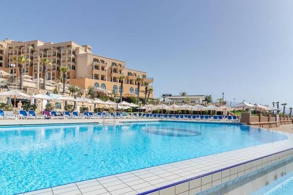Außenpool des Corinthia St George's Bay Hotels mit Sonnenliegen und Sonnenschirmen