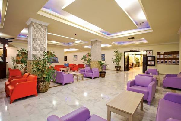 Lobby des Süral Garden Hotels mit violetten und roten Sesseln, Tischen und Pflanzen.