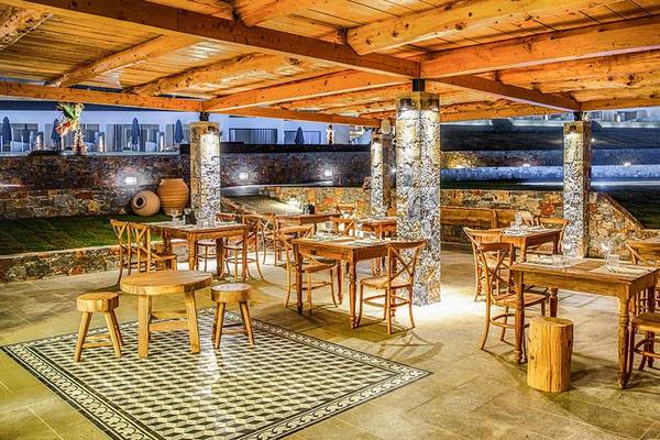 Innenbereich eines Restaurants im Abaton Island Resort & Spa Hotel mit hölzernen Möbeln und Beleuchtung.