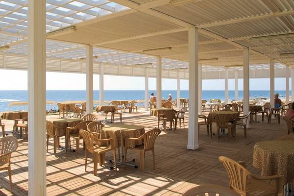 Foto der Terrasse des Süral Garden Hotels mit Blick auf das Meer und belegten Tischen.