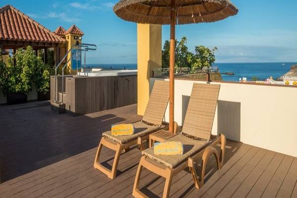 Terrasse des Hovima Jardin Caleta mit Ausblick auf das Meer, zwei Liegen und einem Sonnenschirm