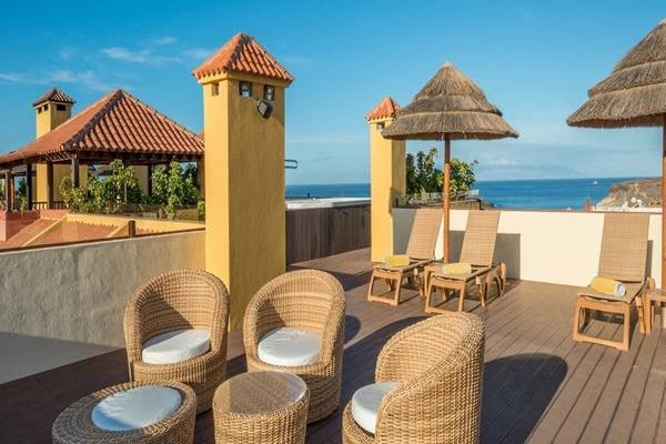 Terrasse des Hovima Jardin Caleta Hotels mit Blick auf das Meer, Lounge-Sesseln und Sonnenschirmen.