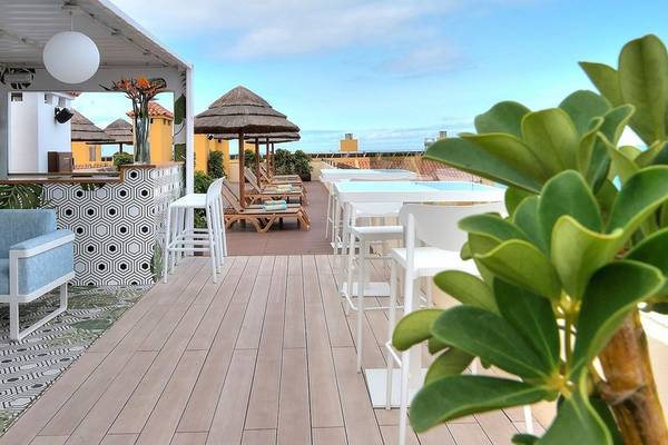 Dachterrasse des Hovima Jardin Caleta Hotels mit Loungebereich, Sonnenschirmen und Bar