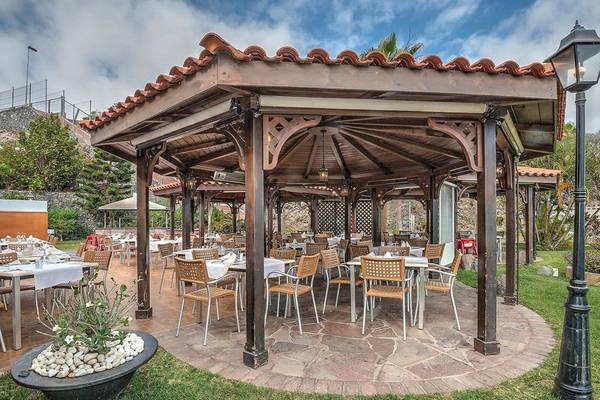 Gartensitzbereich des Hovima Jardin Caleta Hotels mit runden Tisch und Stühlen.
