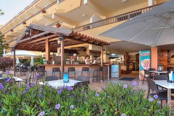 Außenbereich des Hovima Jardin Caleta Hotels mit Bar und Tischen im Freien