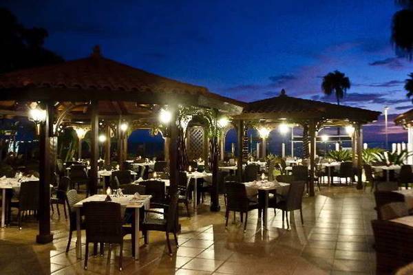Hovima Jardin Caleta Hotel Außenbereich bei Nacht mit beleuchteten Tischen und Stühlen.