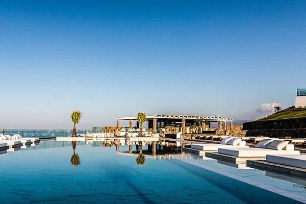 Infinity-Pool des Abaton Island Resort & Spa mit weißen Liegen und Blick auf das Meer.
