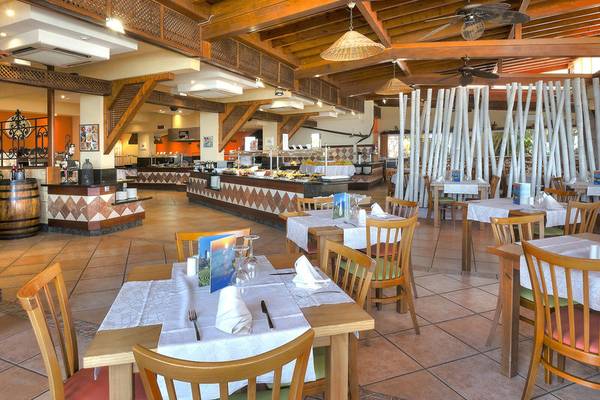 Innenansicht des Restaurants im Hovima Jardin Caleta Hotel mit Holztischen und Stühlen, Buffet und hölzerner Decke.