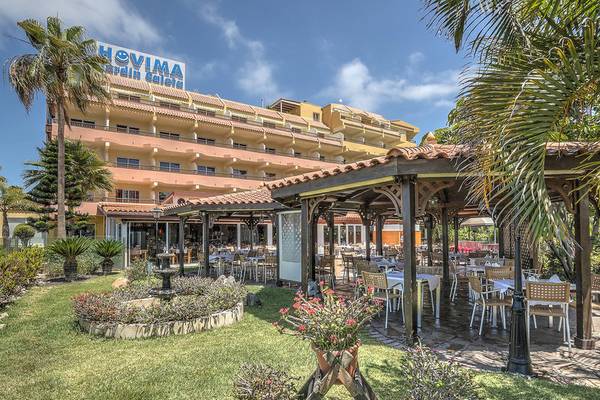 Außenbereich des Hovima Jardin Caleta Hotels mit Garten, Tischen und Stühle.